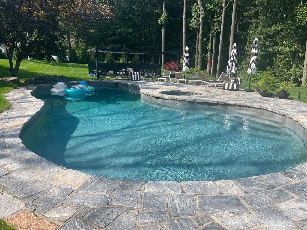 Freeform pool with a stone patio built by GR Concrete Works in Connecticut