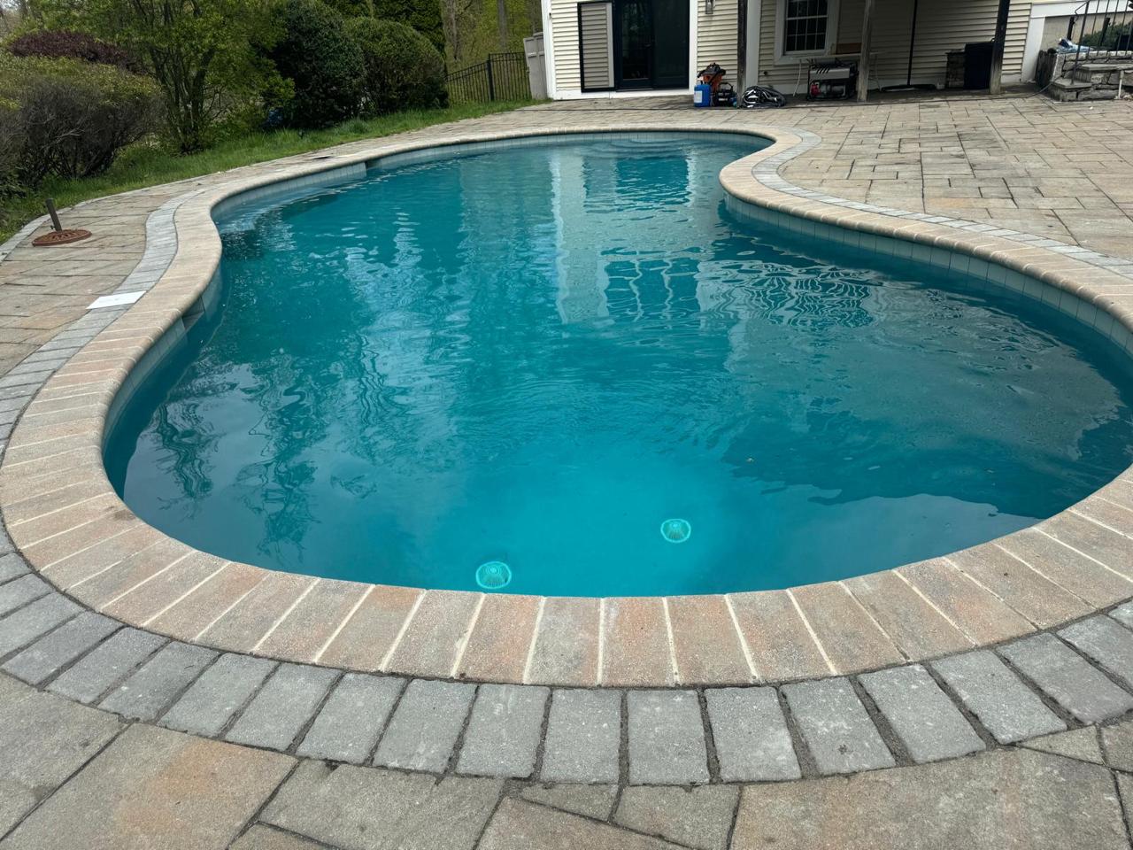 Freeform pool with brick coping and patio