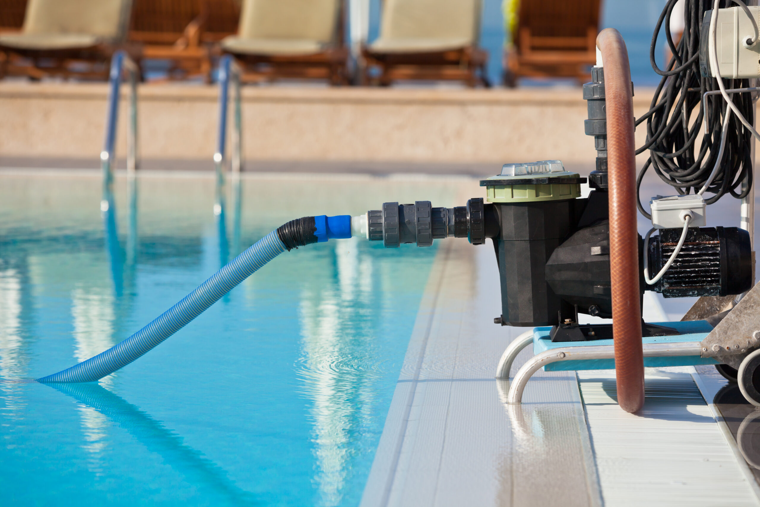 Pool pump and hoses running beside a residential pool